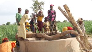 Des jeunes filles et femmes entrain de puisées de l'eau dans un puits
